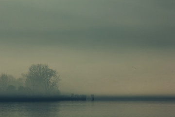 Fototapeta na wymiar Ioannina lake in Epirus Region, Greece. Artistic panoramic view with natural reflection in the water and fog.