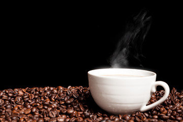 Steaming coffee cup on coffee beans in close up photo. Refreshing beverage in the morning