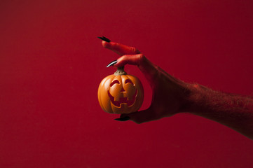 Red monster devil hand holing a pumpkin