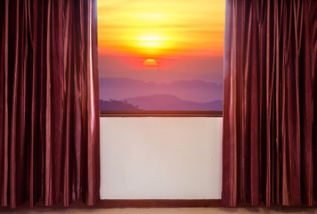 windows with curtains and blinds looking out the window frame meet high view sunrise over rainforest mountain in early morning
