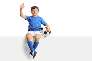 Foto op Plexiglas Small boy with a football sitting on a panel and waving © Ljupco Smokovski