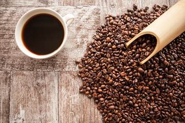 Naklejka premium Top view of Coffee cup on coffee beans in close up photo. Refreshing beverage in the morning