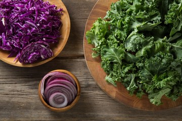Fresh kale leaves with red cabbage and onion on table