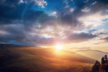 Fototapeta na wymiar Beautiful dramatic sunset in mountains. Landscape with sun light shining through clouds