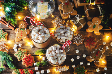 Dark wooden background with cocoa, gingerbread cookies, Christmas trees and gifts