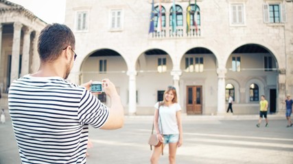 Young happy couple making photos in a tourist place on their vacation