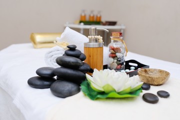 Fototapeta na wymiar stones for massage , massage oil and a flower in Spa salon