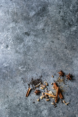 Variety of spices cinnamon, cardamom, anise, sugar and dry black tea over dark texture surface. Top view with space. Food background.
