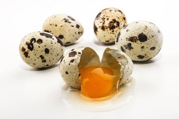 quail eggs and an open egg on bright background