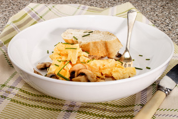 scrambled eggs with mushrooms and chives served in a dish