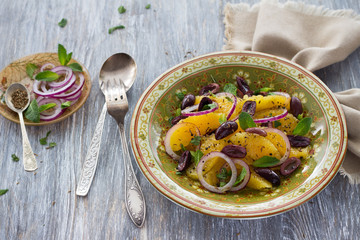 Moroccan salad of oranges with red onions, olives and cumin on a wooden table