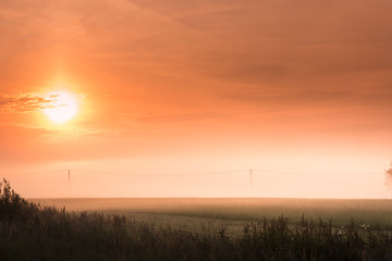 Colorful autumn sunset with sun rays coloring clouds in red