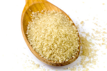 wooden scoop spoon of brown cane sugar with pinch of sugar spilled around on white background.