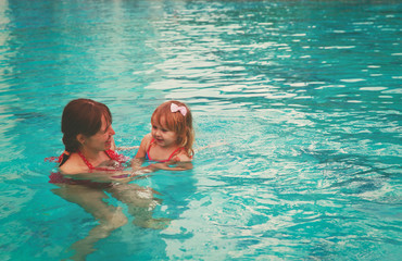 mother teaching little daughter to swim