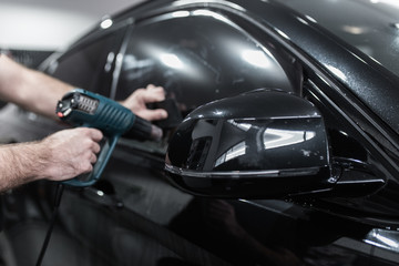 Car tinting - Worker applying tinting foil on car window.