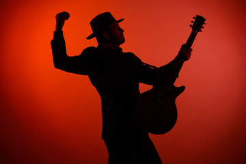 silhouette of a musician playing instrument in a hat