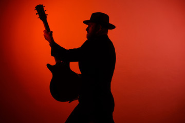 silhouette of a musician playing instrument in a hat