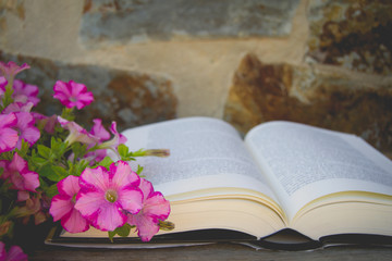 Old book and bouquet of flowers. Open book with pink flowers. Vintage style. Summer or spring season. Nostalgic vintage background. Old book with romantic pink flowers.