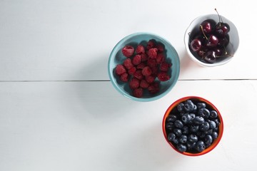 Overhead view of berries and cherries in bowls