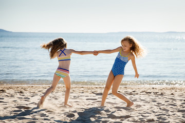 Two sisters dancing on a sandy beach