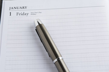 Metal pen on a calendar with the page showing the first day of the year in a setting goals concept