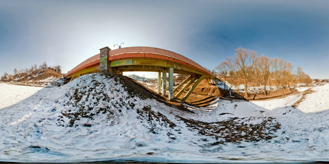 Winter panorama in the snow-covered forest near the bridge in nice sunny evening. Full spherical...