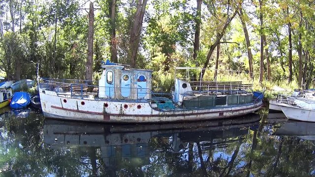 Old abandoned boat moored against jetty in canal