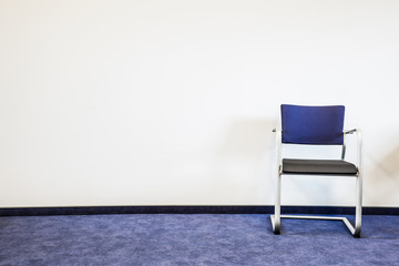 Chair on the blue carpet floor at the wall. Waiting room in office, hospital, clinic, education or...