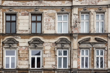 Fototapeta na wymiar The facade of the old shabby brick house with Windows