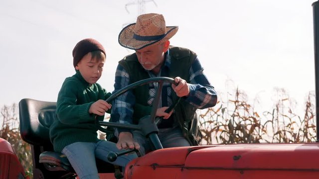 Grandfather teaching his grandson how to drive a tractor