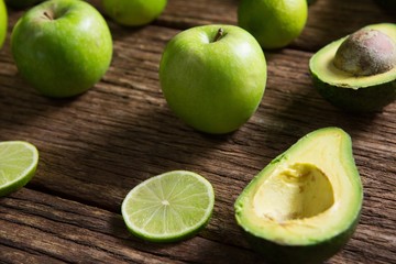 Lemon slice, avocado and green apple arranged on wooden table