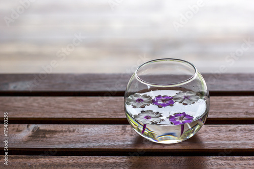 Round Glass Vase With Floating Flowers On A Wooden Table With A