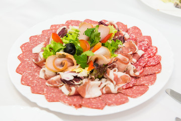 Plate of cold meats in the restaurant. Meat snacks. Smoked sausage and bacon,