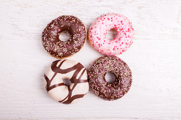 Over top view of Different type of donuts on white wooden background. Delicious junk food