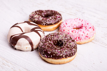 Overtop view of donuts on white wooden background. Delicious junk food