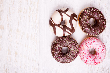 Overtop view of donuts on white wooden background. Delicious junk food