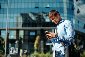 Young businessman online via smartphone in the city