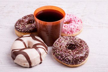 Different type of donuts on white wooden background next to a glass of cola. Delicious junk food