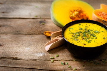 Vegetable and lentils creamy soup, cut pumpkin, seeds, parsley on rustic wooden background. Top view, copy space
