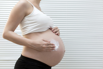 Fototapeta na wymiar Pregnant woman using moisturizer