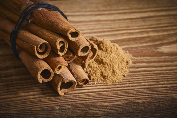 Zimtstangen und gemahlener Zimt auf Holz