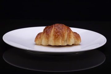 Tasty croissants with plate on black backgound