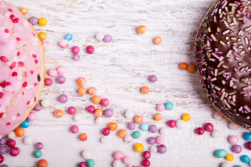Close up of Different type of donuts in and sweet candy on white wooden background. Delicious junk food