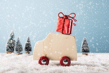 Wooden toy car in winter landscape with gift box