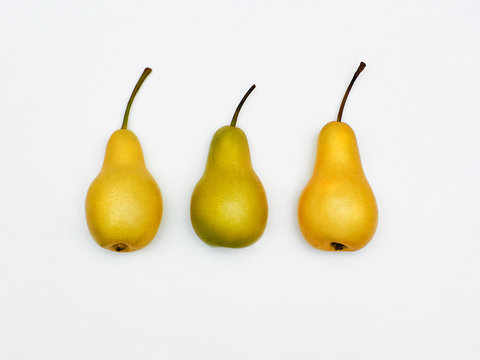 Pears Top view Two yellow pears and one green pear are lying in a row on white background Isolated seasonal fruit Flat lay