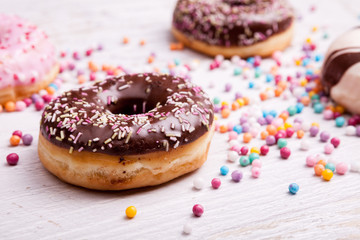 Close up of Different type of donuts in and sweet candy on white wooden background. Delicious junk food