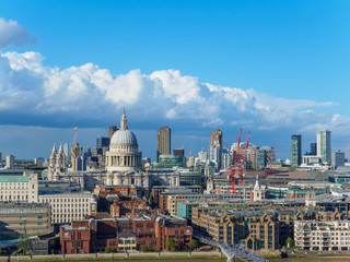 London skyline with a view of St Paul's Cathedral, Millennium Bridge and skyscrapers of the north bank of the River Thames on a sunny day.