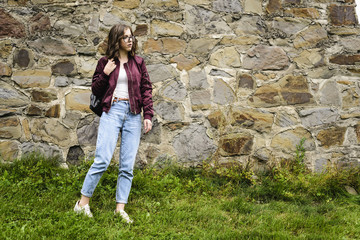 Fototapeta premium young girl with glasses posing near a wall of stones