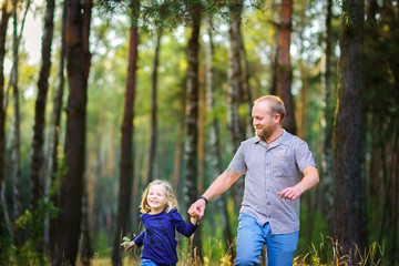 Happy family walks in the evening park, holding hands and having fun