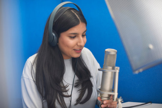 Young female college student at microphone in TV recording studio
